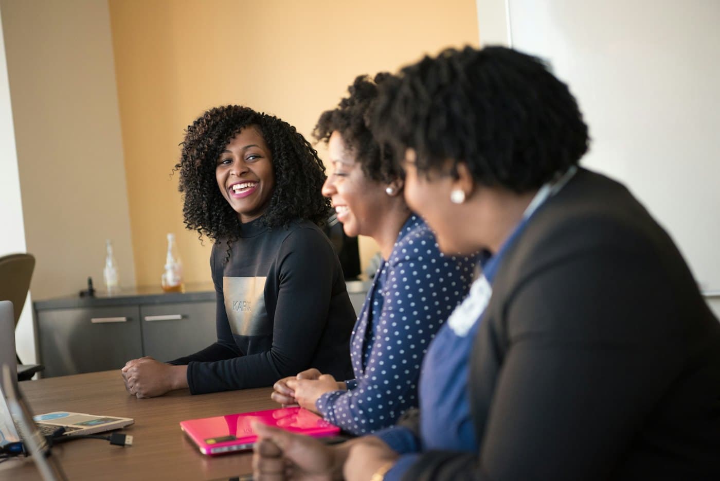Three colleagues laughing together at a meeting table